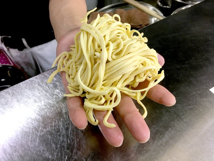 家系ラーメンではおなじみ、酒井製麺製のやや平打ちの中太ストレート麺。均一にゆで上がるように軽く揉みほぐす。