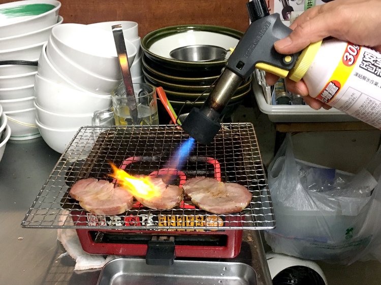 チャーシューは提供する直前にバーナーで炙る。バーナーの先につけたフィルターがガス臭や焦げを防いでくれる。