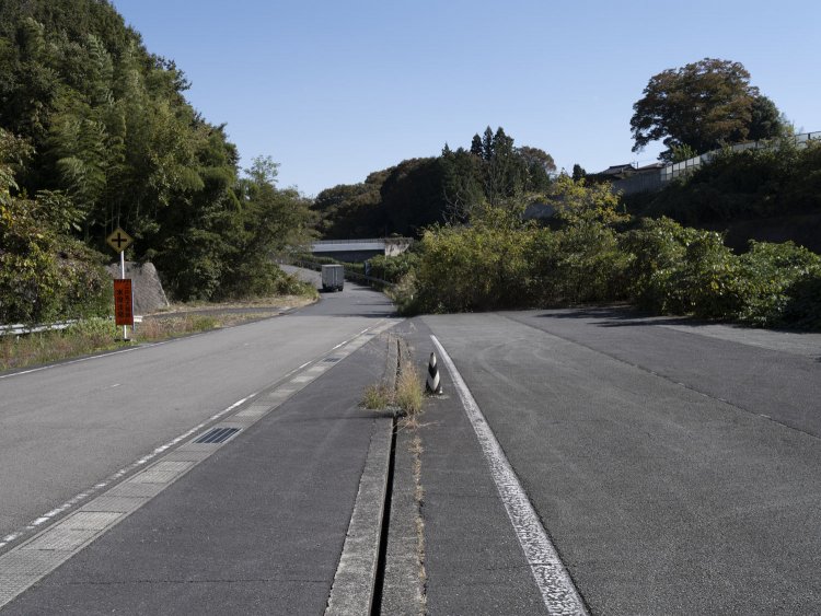 再び現れる現在線との合流地点。中央分離帯であった箇所には深い溝が……。溝の左側には分離帯の盛り上がり部分があったものの、一般道化によって削られている。