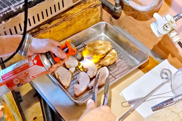 鶏胸肉と豚肩ロースのチャーシューを炙っているところ。盛り付ける前のひと手間を惜しまない。