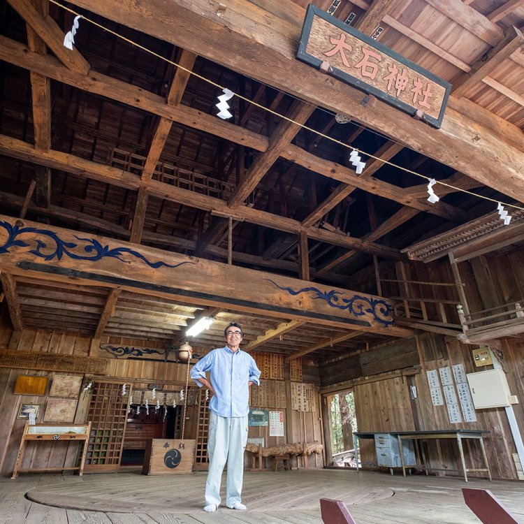 神楽殿に立つ氏子総代の河内正道さん。2階部分の楽屋も見事だ。