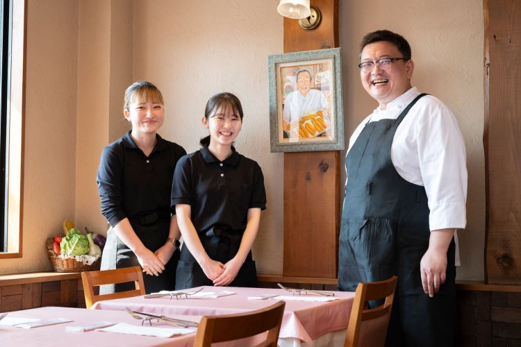 南イタリアで修業した店主の飯沼祐太さんと、スタッフの皆さん。店内には先代店主の絵が飾られている。