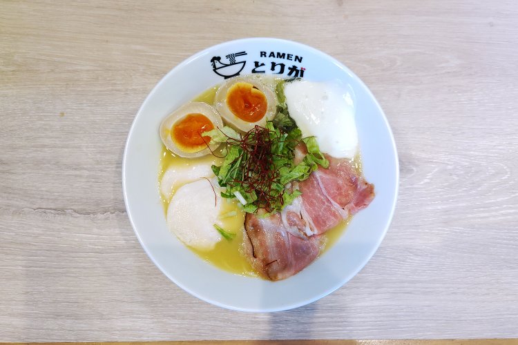 具材盛り盛りの鶏濃めん塩Rich。味玉はカットされていて食べやすく、器に暖色を添える視覚効果も。