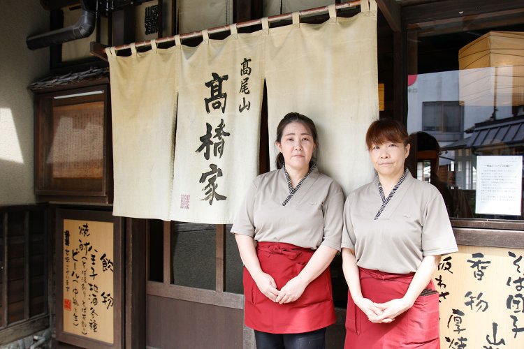 花番さんをまとめるホール主任の西川ゆかりさん（左）。「とろろにそばをつけるか、そばの中にとろろを入れるかは自由です。刻み海苔とワサビ、七味で調整しながらどうぞ」