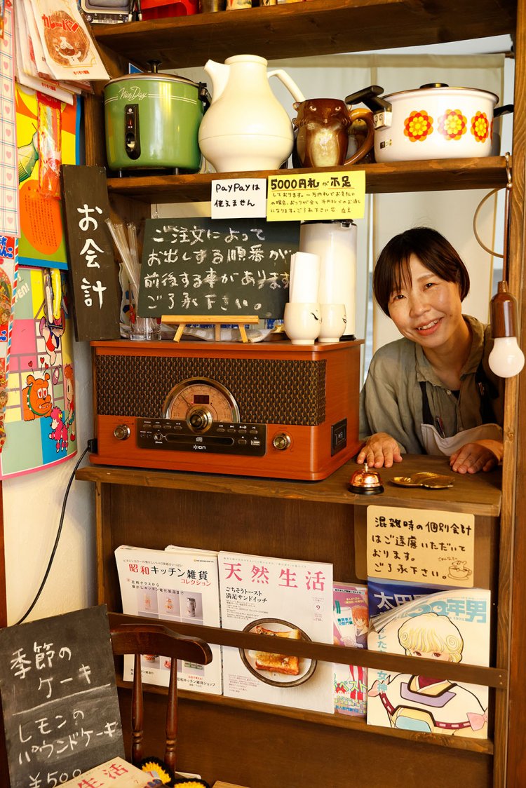 昭和家電が並ぶお会計場所から顔をのぞかせる小宮山さん。