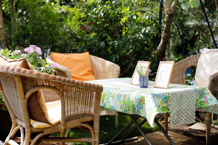 クレマチスのアーチの下に籐製のイス席が。緑に埋もれるよう。