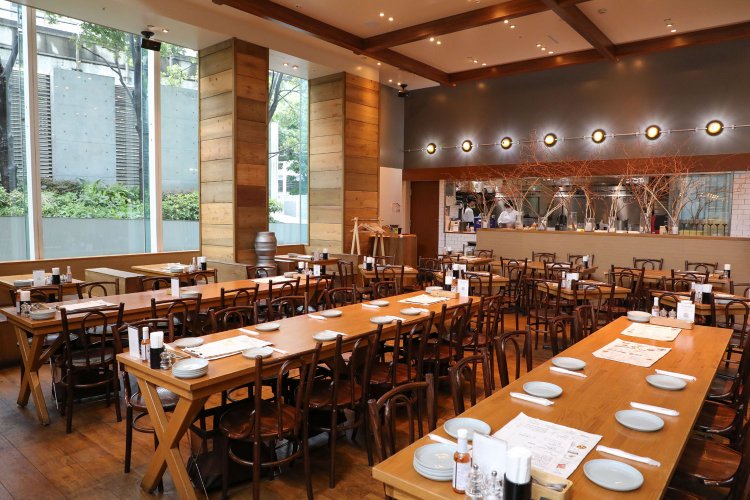 天井が高く広々していて開放感がある店内。ウッディでナチュラルな雰囲気も心地よい。オープンキッチンからの活気も伝わってくる。