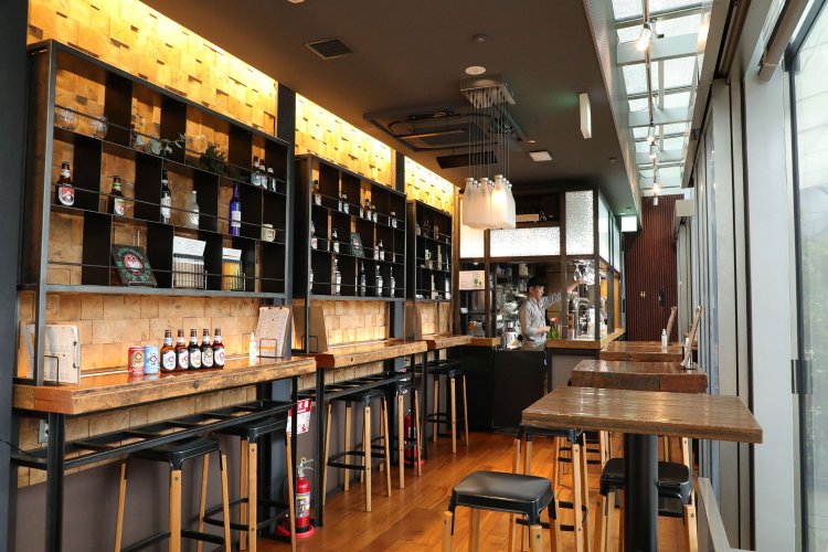 飾り棚に自社ビールが並ぶ、木のぬくもりが感じられる空間。カウンター席とテーブル席があり、八重洲の景色を眺めながらビールを楽しめる。