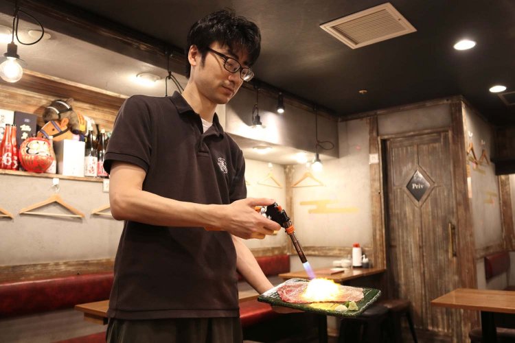 名物さしとろ979円はお客さんの目の前でガスバーナーを使い炙ってから提供する。