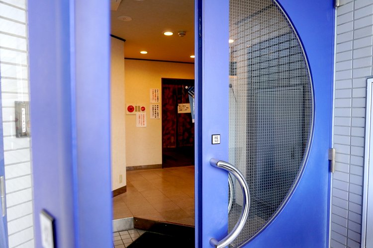 青い扉を開けた先に見える店の入り口。