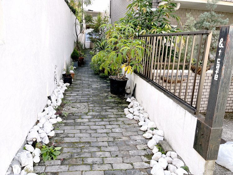 塀の角にさりげなく記された『＆t cafe』の文字。あ、この路地を入るのね……。