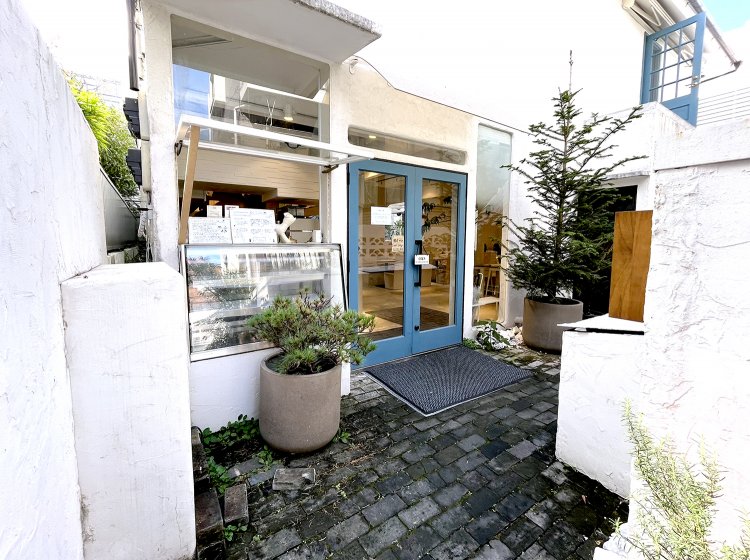 住宅地の細い路地を入った先にある。白い壁に青いドアが爽やか。