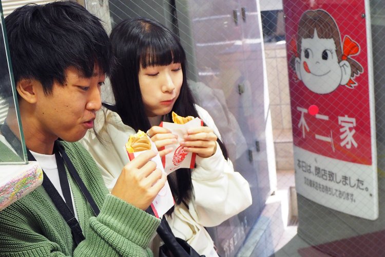 「生地がとってもやさしい味」とゆうきさん。 店内にあるベンチにすわって頬張る。