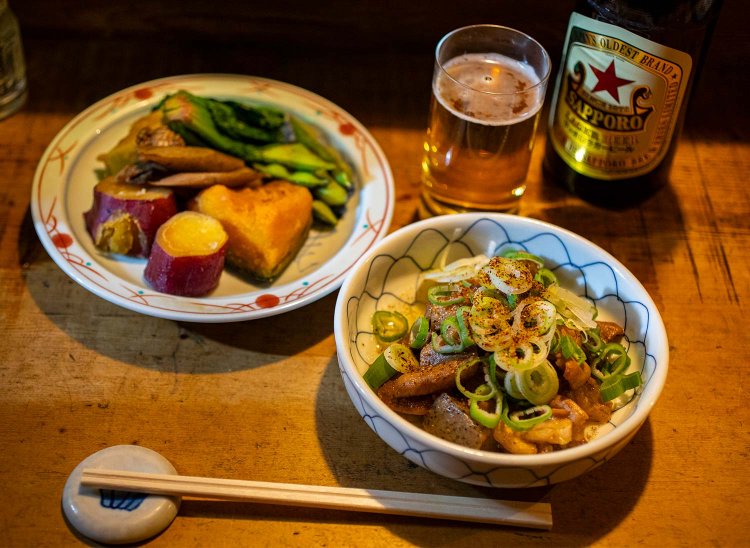 品書きにあるものが食べられるとは限らない。売り切れ多数もご容赦を。常連は慣れたもので「今日、何がある？」から注文が始まる。写真は総菜盛り合わせともつ。