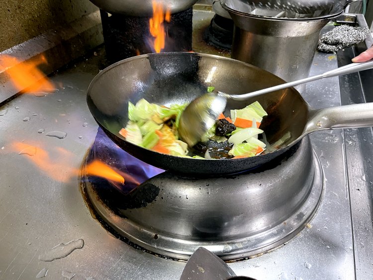 広い厨房には渉さんを含めコックさんが５人いて、次々とオーダーを仕上げていく。豚バラ肉や野菜など具材を手早く炒める。