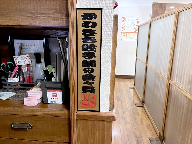 レジの横に掲げられていた「かわさき餃子舗の会」の証。