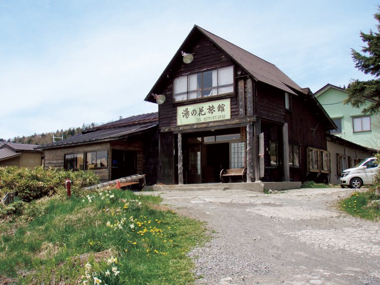 万座温泉のなかでも最も高所に立地。山小屋風の佇まいが青空に映える。