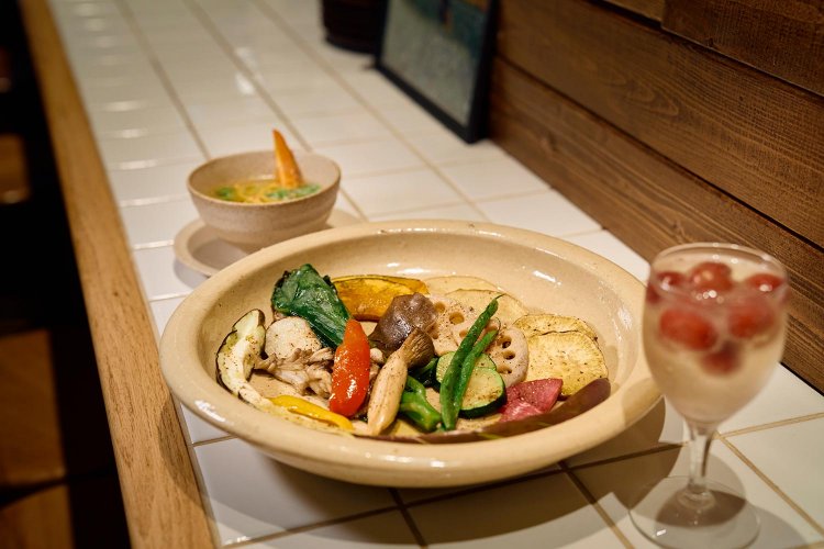 旬野菜のロースト1200円、昼のラーメンスープのベースにもなるお通しの塩麹のスープ550円など。