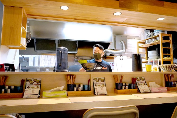 店主の市原俊輔さん。カウンター越しに客との会話を楽しんでいる。