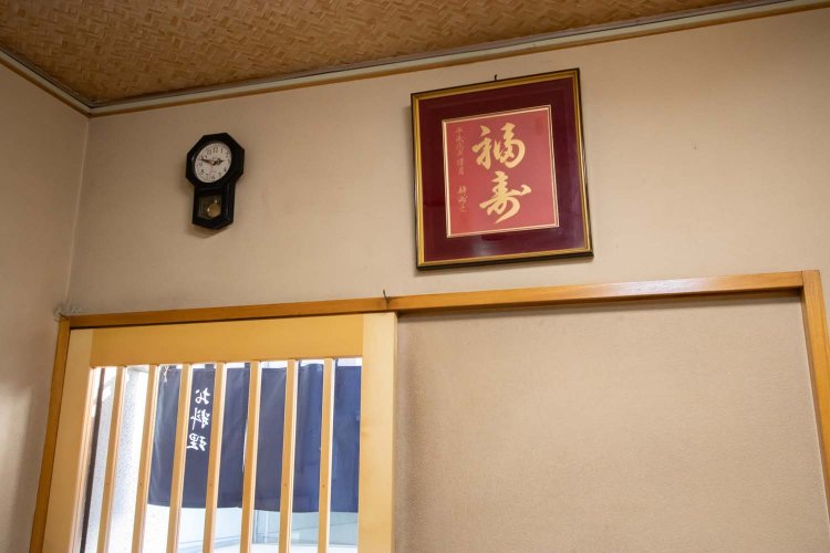 柱時計風の掛け時計に「福寿」の額。昭和レトロが微かに香る。