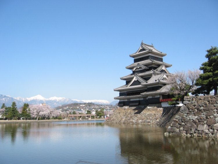 西側に穂高岳をはじめとする北アルプスを眺望。堀の水面に山並みが映る。