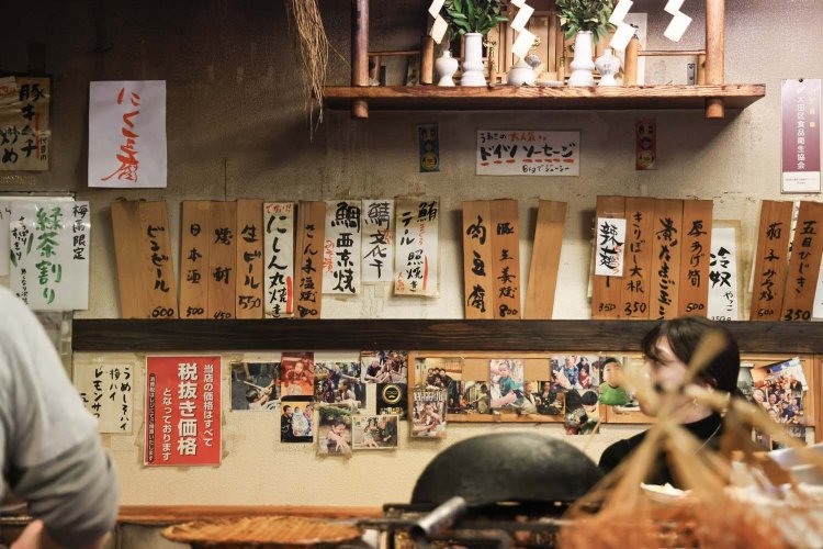 年季の入った壁に、お品書きの木札がずらり。BGMはテレビの音。