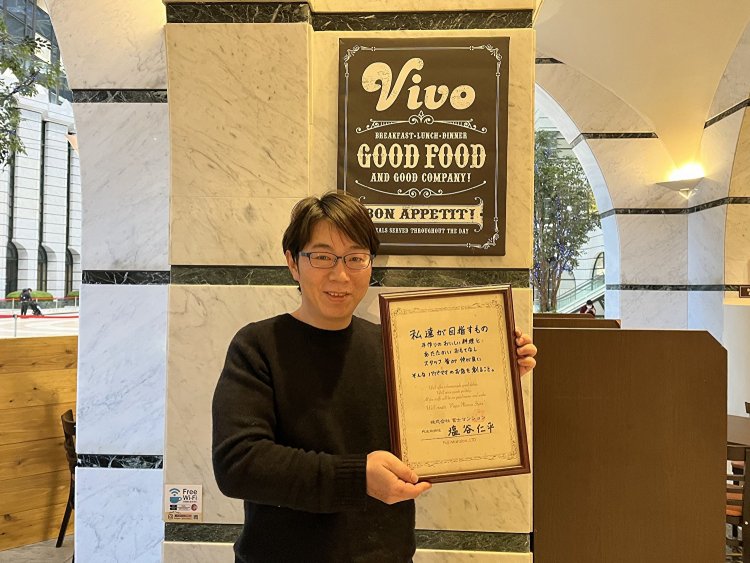 「私達が目指すもの」が書かれた表彰盾を手に持つ店長の小濵さん。