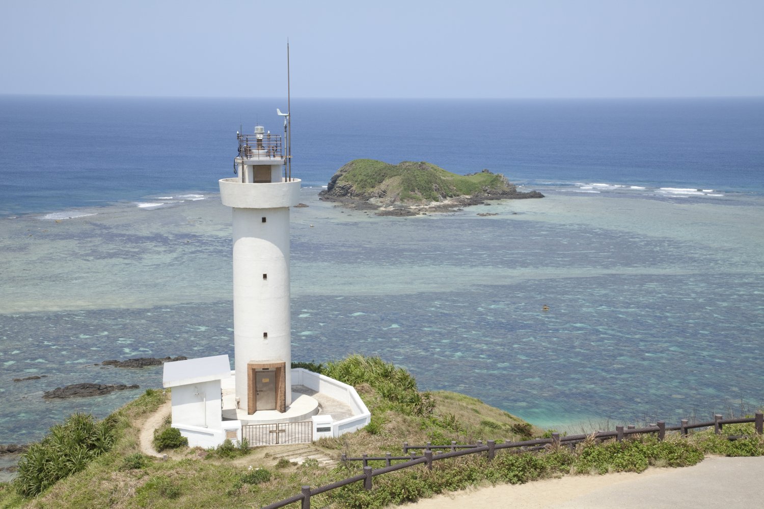 白亜の平久保崎灯台と、変化に富むブルーの海とのコントラストに見とれる。（写真／沖縄観光コンベンションビューロー）