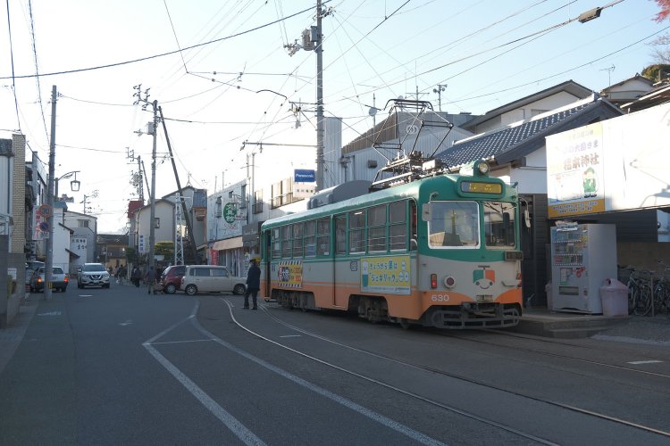 伊野電停へ到着。軌道が2線に分岐し、それぞれに乗り場がある。手前の白線枠が乗り場。電車の先には……。