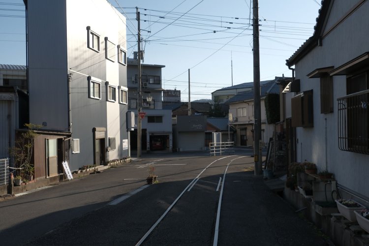 住宅地のなかに一本の軌道が伸びている。既に架線は撤去されていた。左手の生活道路と段差ができ、軌道跡は上り勾配となっている。