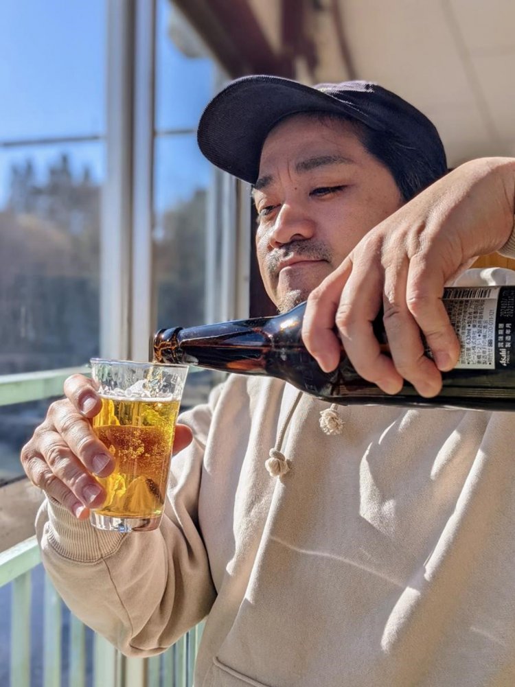 入間川を望みながらビールを注ぐ筆者。