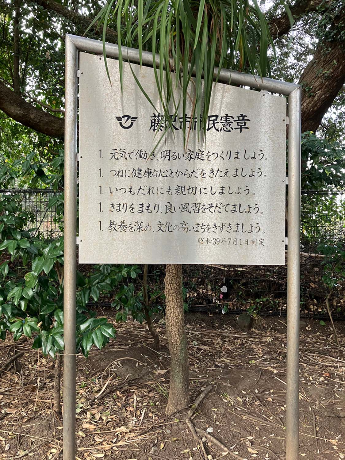 江の島に設置されている金属板市民憲章。後ろの木が成長すると、文章が隠れてしまう危険がある。