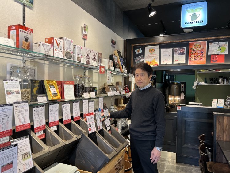 オーナーの山本さんとコーヒー豆の並ぶ店内。
