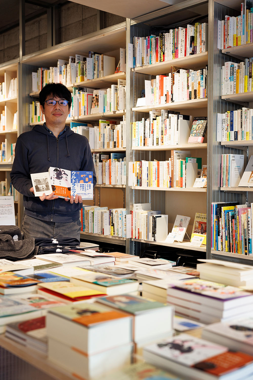 店長の遠井大輔さん。入り口の平台に並ぶのは「働くこと自体を考える本」。
