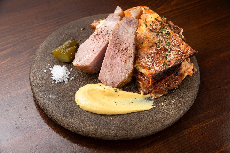 岩手 氷温熟成豚 肩ロース150g2200円（左）と牛すじトマト煮込みラザニア2人前1800円。