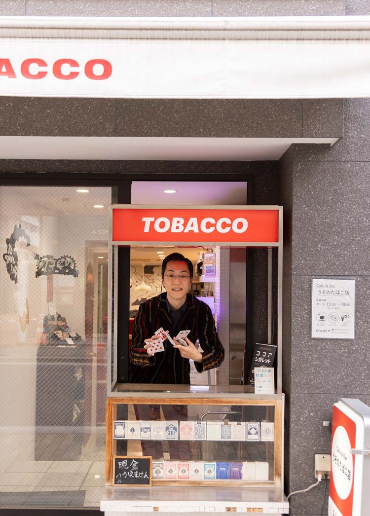 タバコのショーケースと店主･大川原脩平さん。カードさばきが見事だがマジシャンではない。