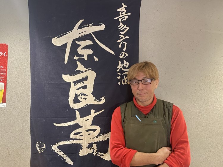 オーナーの五味敦さん。後ろには懇意にしている夢心酒造の日本酒・奈良萬の旗。