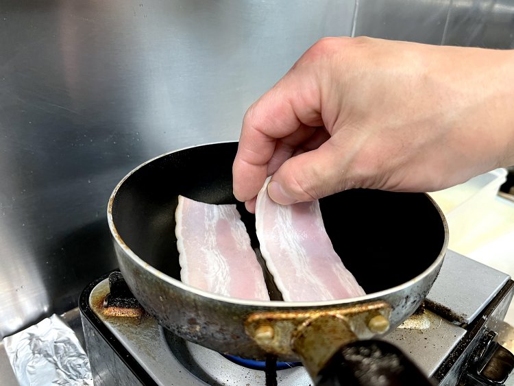 小さなフライパンに油を敷き、温まったらベーコンを2枚置く。