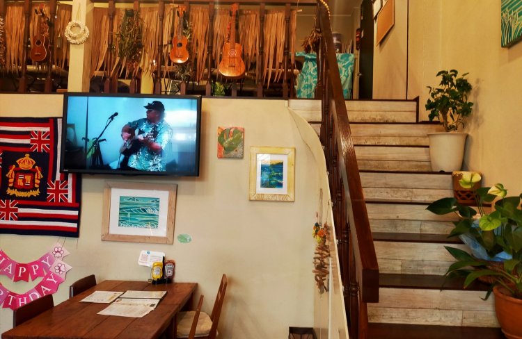 店内の様子。ハワイアン音楽演奏の様子が流れ、ウクレレが飾られている。階段の雰囲気も可愛らしい。
