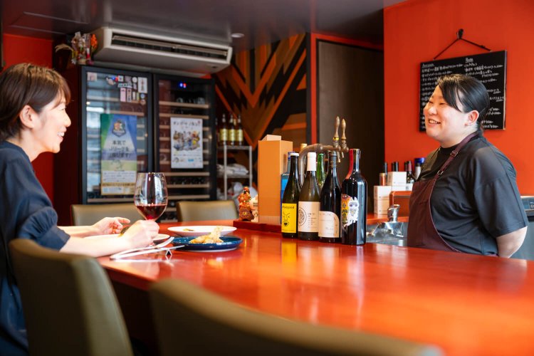 オレンジの壁が印象的な店内。オーナーシェフの内野さん「長野ワイン応援団として、八王子でがんばります！」。