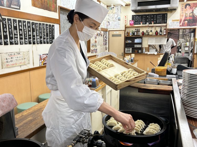 一つ一つ丁寧に鉄鍋に餃子を並べて焼いていく王さん。野菜とにんにくの匂いが香る。