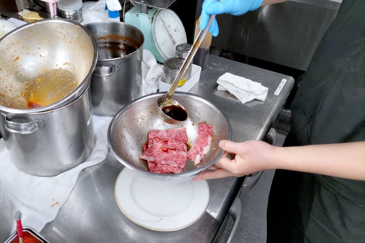 お肉にオリジナルの生ダレをかけるところ。この後にゴマやネギなども加えていく。