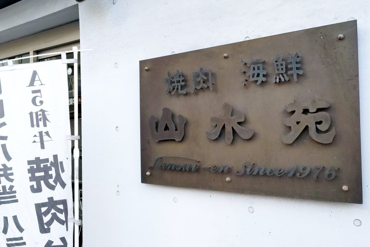 出入り口の脇に掲げられている店名のプレート。地元で愛される老舗焼き肉店の風格が漂う。