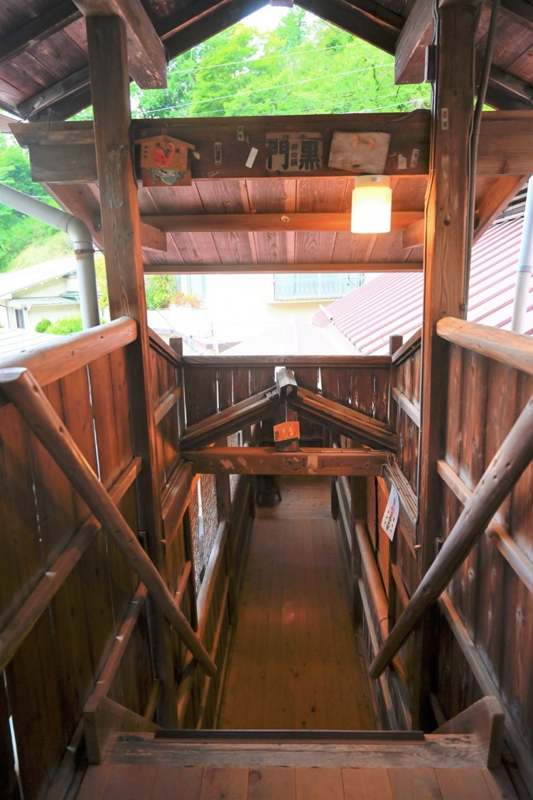 まるで神社のような荘厳な雰囲気を湛えた、混浴大浴場への入口。渡り廊下を通り、木の階段を7段下ると湯殿がある。