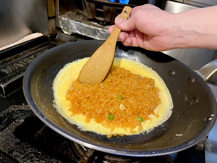 卵で玉ねぎ、グリンピースが入ったチキンピラフを包み込む。