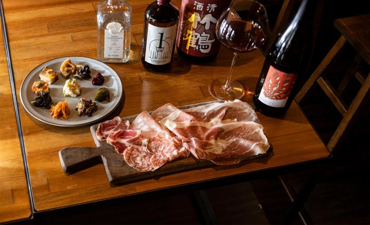 生ハム＆サラミ盛り並990円。生ハムはフランスのオーベルニュ地方のものでふわっとなめらか。前菜盛合せ1100円。グラスの赤ワインは“うす旨”の「オートル・ショーズ」1155円。