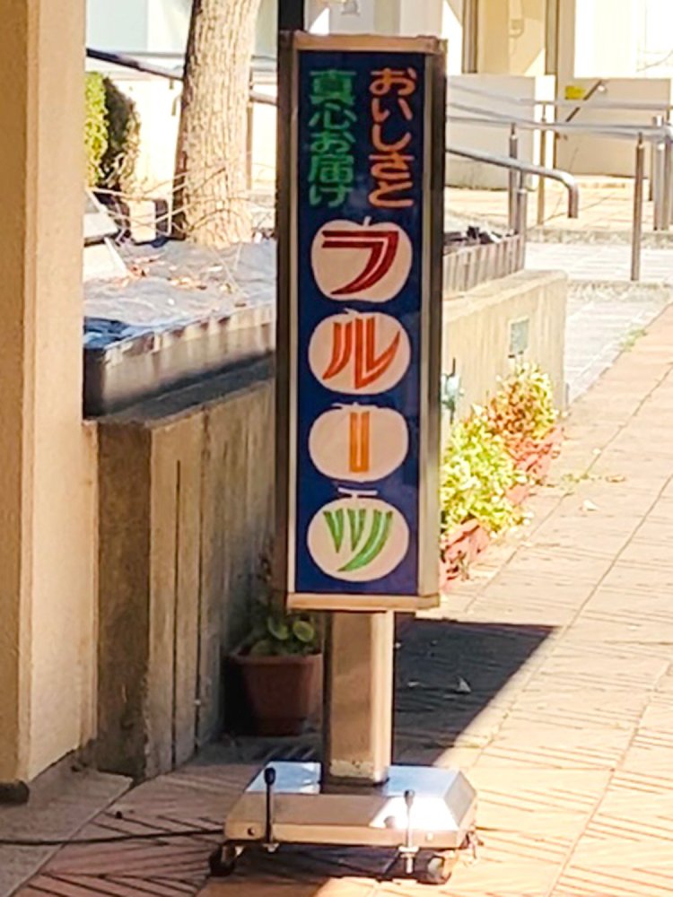 カラフルなフルーツのイラストもかわいらしい、果物店の三角柱看板。いつまでも眺めていられる。