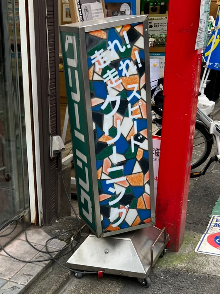 デザイン性の高いモザイクタイル背景にそぐわぬ「走れ！走れ！」の文字。ちなみに残り1面も「Spped Cleaningドライ品即日仕上げ　但し、特殊品は除く」というスピード感ある宣伝が書かれている。