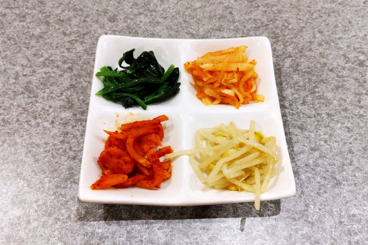 豆もやし、大根、ほうれん草のナムルと、たくあんキムチの4種盛り。いずれも自家製で、ライスによく合う。