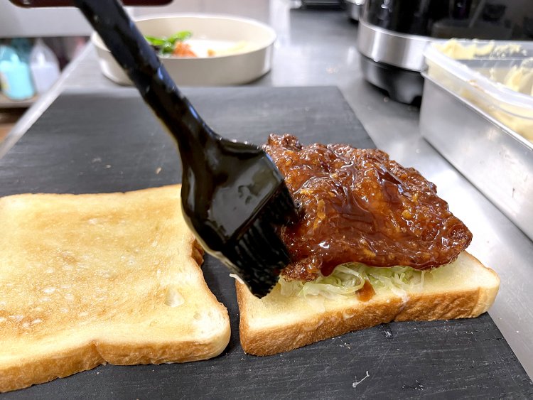 ミルフィーユカツに特製ブレンドのソースをたっぷりかける。はい、コレおいしいヤツ確定〜。